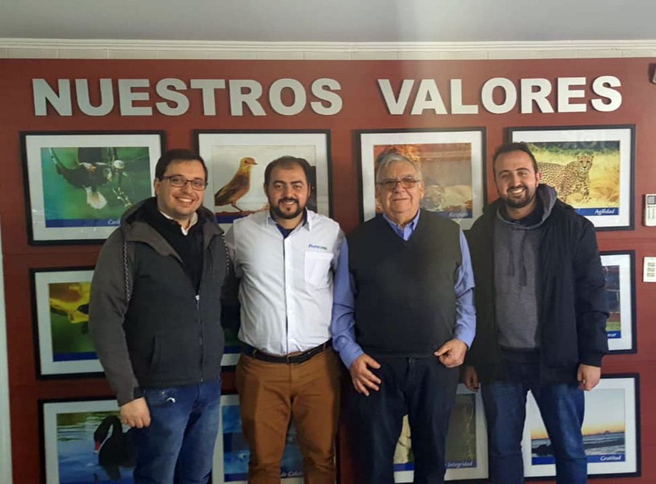 Quatro homens estão posando para uma foto em frente a uma parede que diz nuestros valores