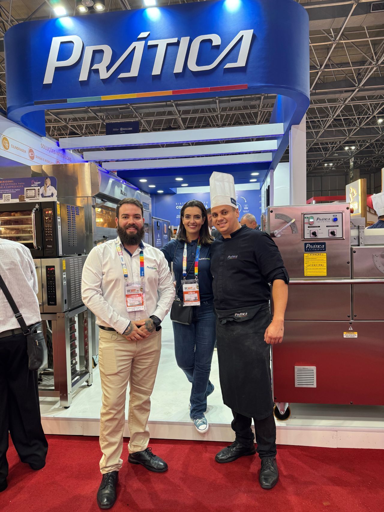 Três pessoas estão posando para uma foto em frente a uma placa de prática.