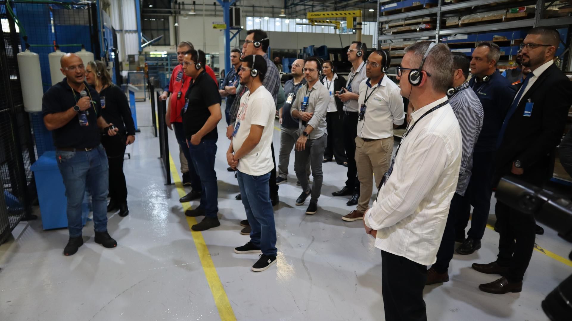 Um grupo de homens está em uma fábrica conversando entre si.