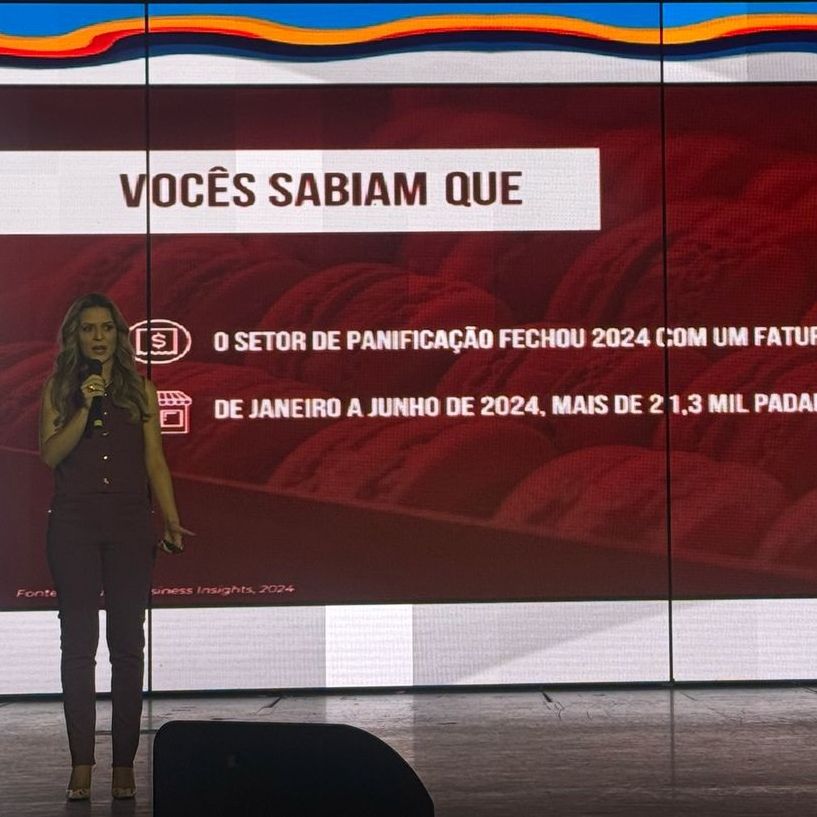 Uma mulher está em frente a uma tela que diz