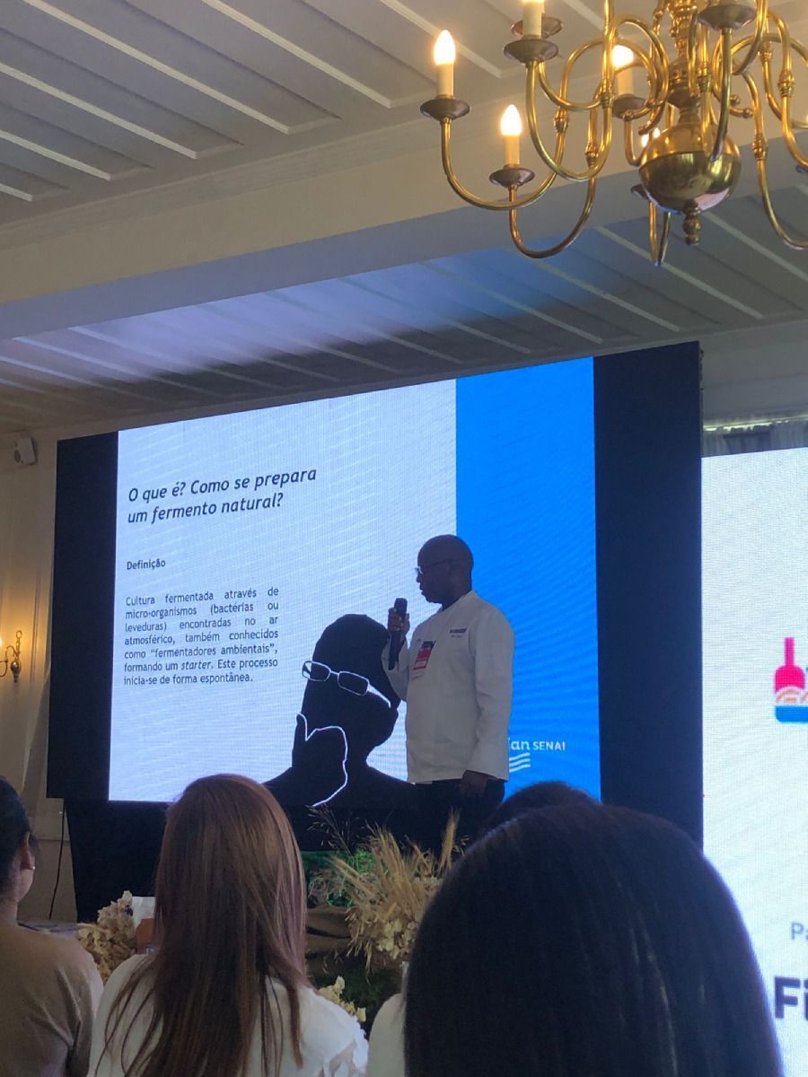 Um homem está fazendo uma apresentação em frente a uma tela grande