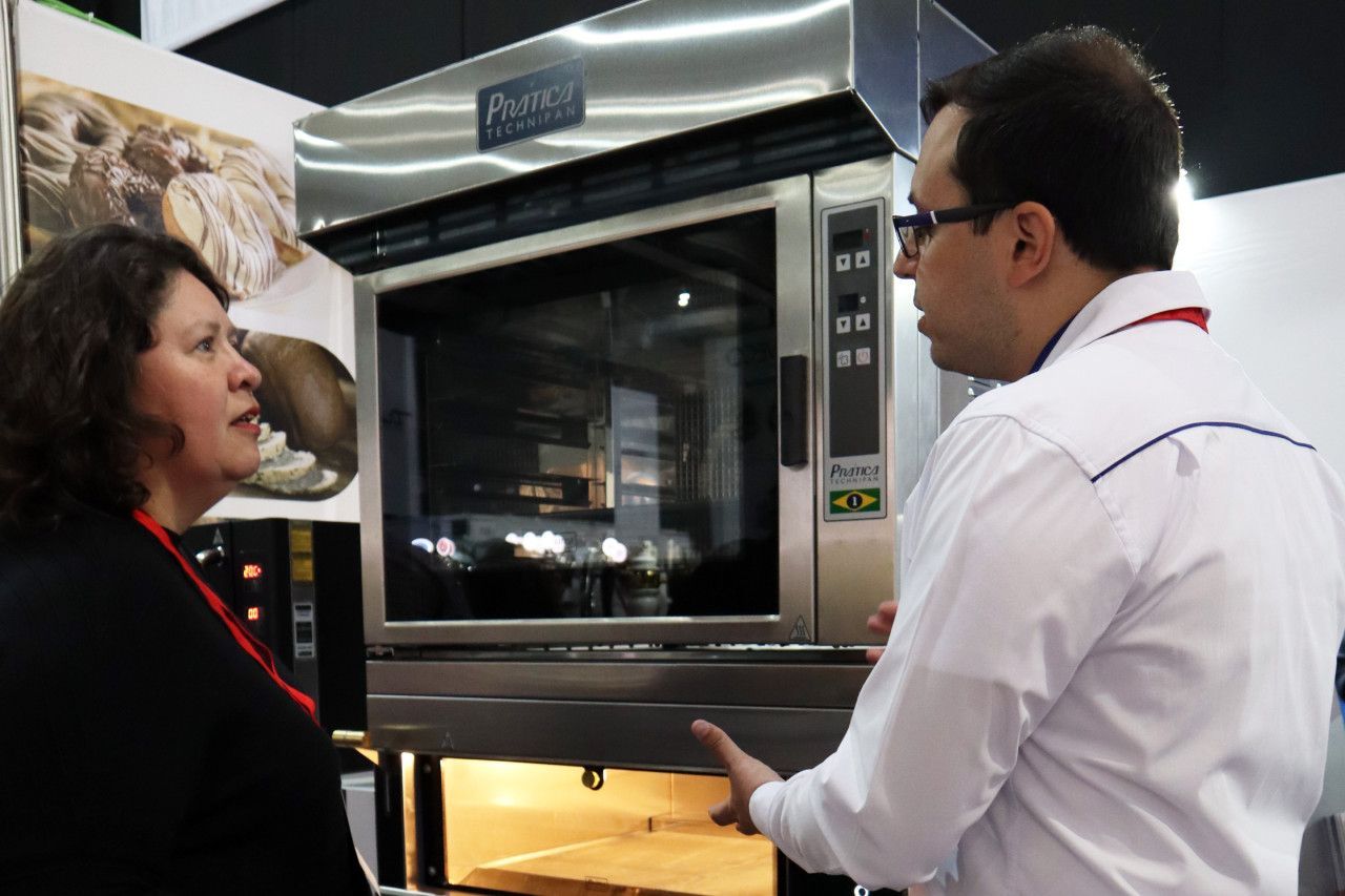 Um homem e uma mulher estão conversando em frente a um forno
