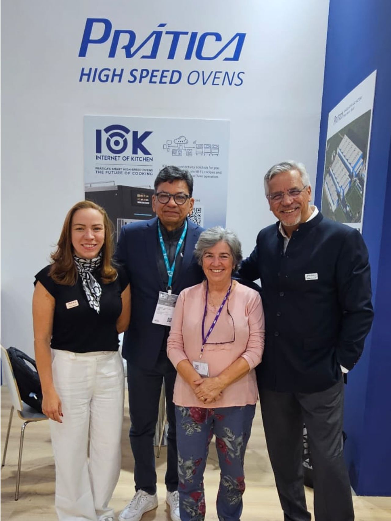 Quatro pessoas posam em frente a um estande da 