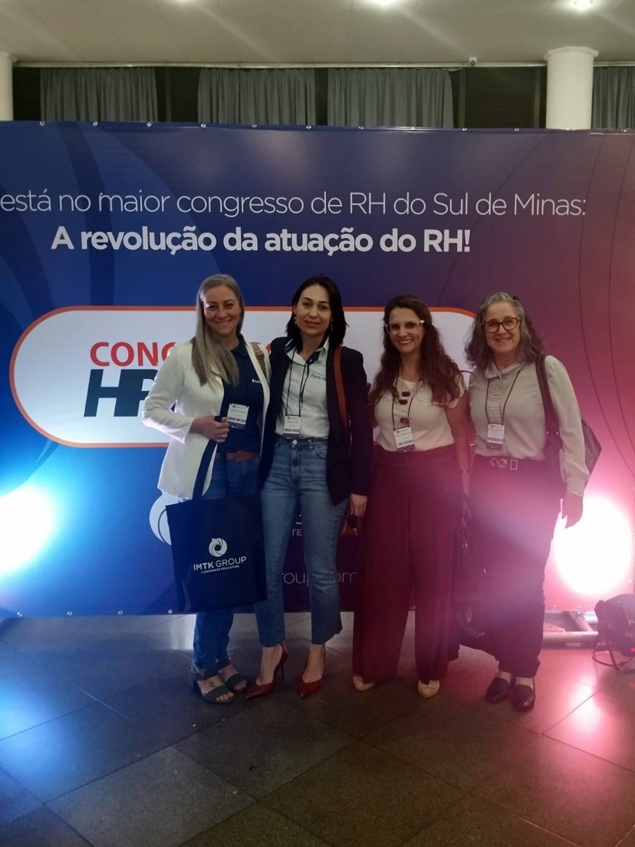 Um grupo de mulheres em pé em frente a uma placa que diz congresso do rh do sul de minas