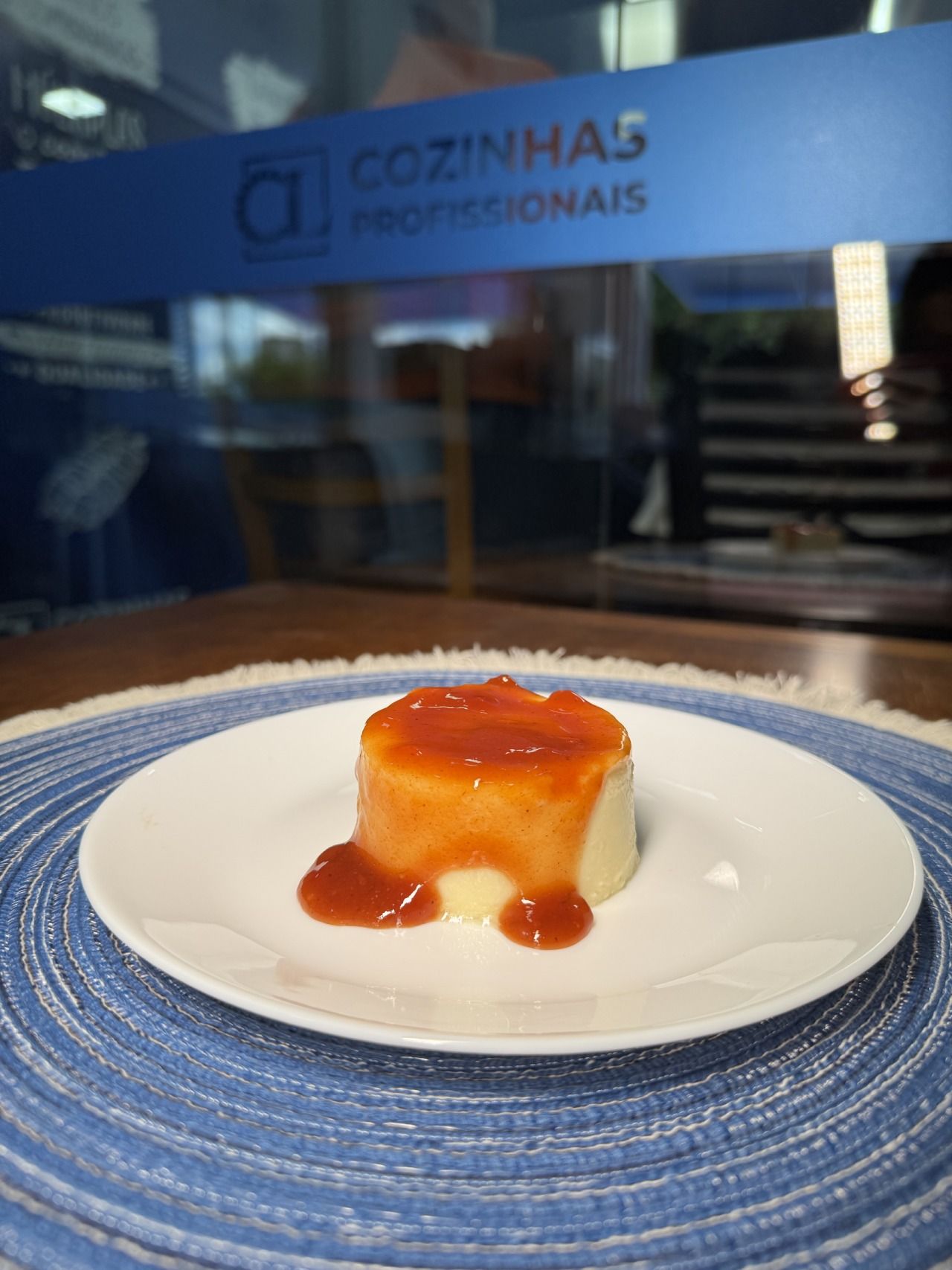 Um prato branco com um pedaço de comida em frente a uma placa que diz cozinhas