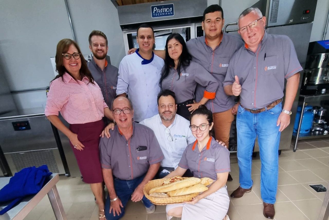 Um grupo de pessoas está posando para uma foto em uma cozinha.