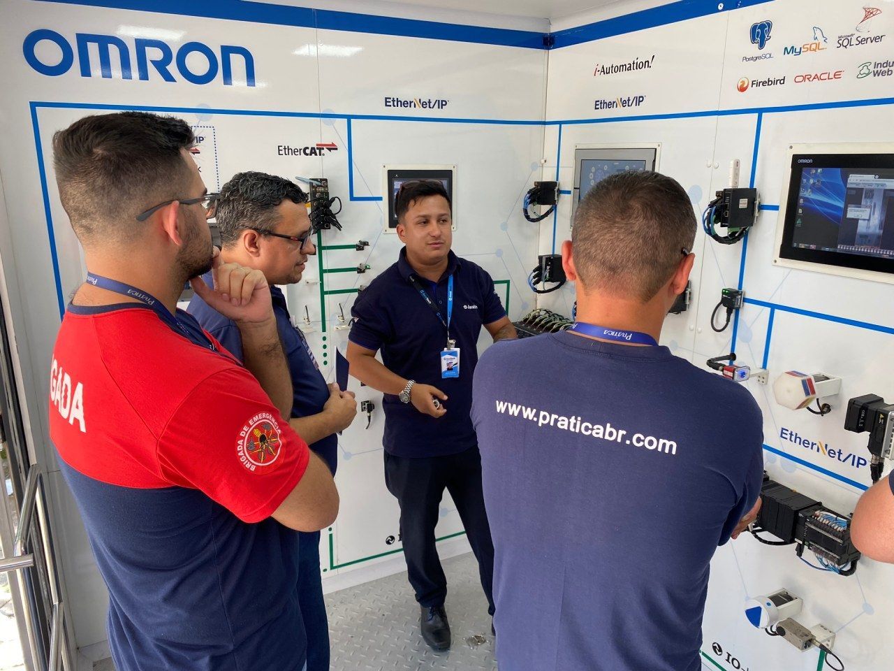 Um grupo de homens está em uma sala com uma placa que diz Omron.