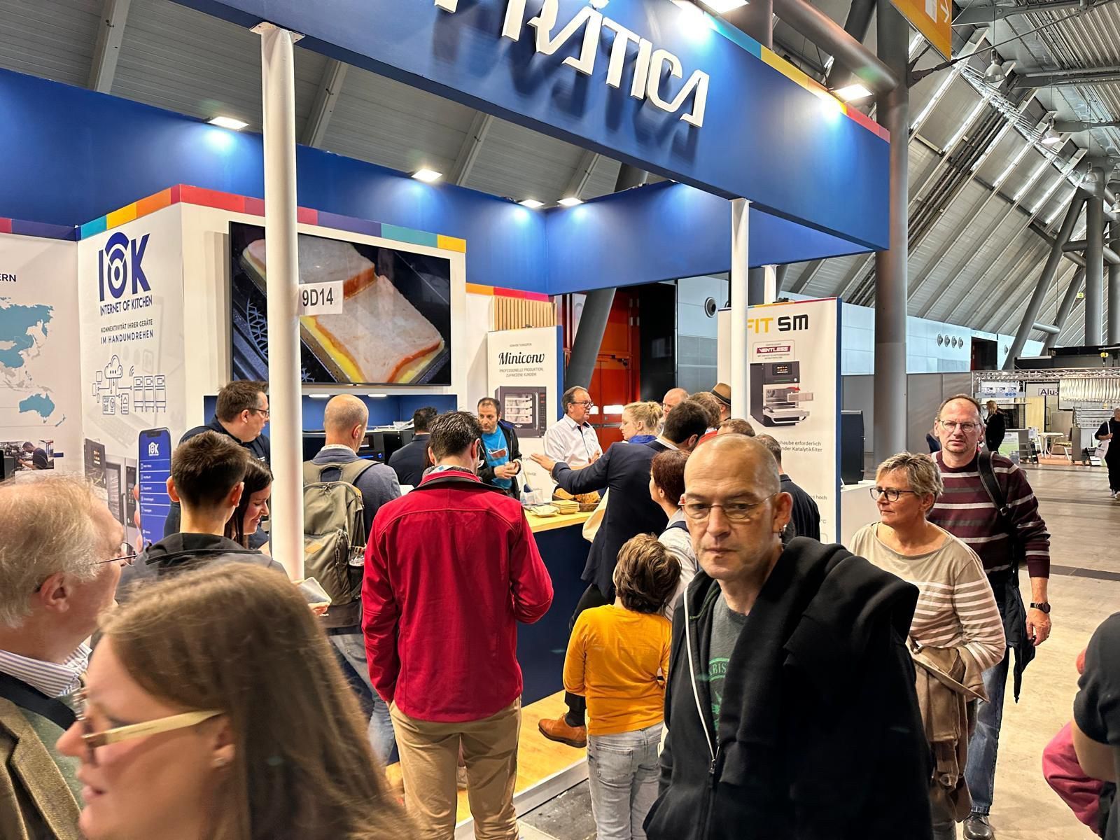 Um grupo de pessoas está em frente a um estande em uma convenção.