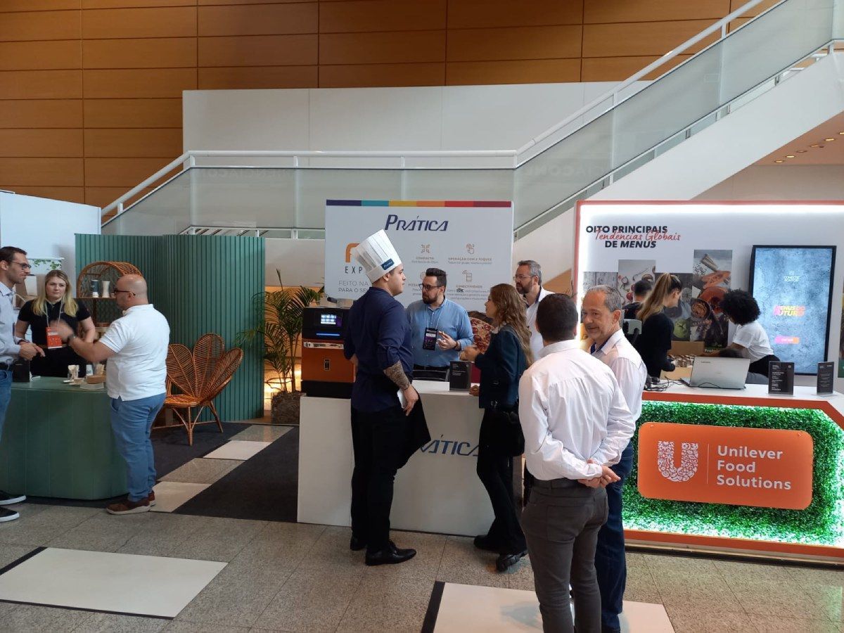 Um grupo de pessoas está em pé ao redor de um balcão em uma sala.