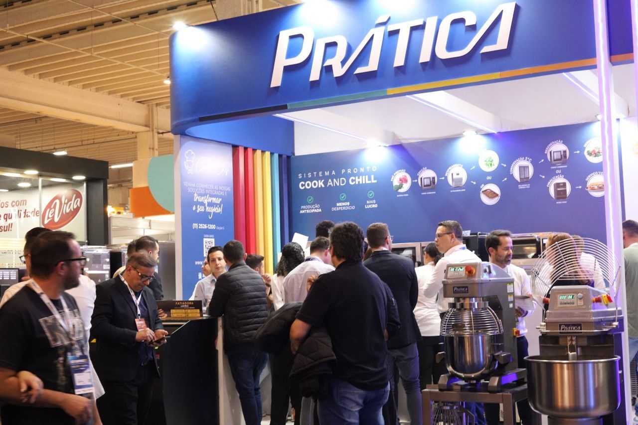 Um grupo de pessoas está em volta de um estande em uma convenção.