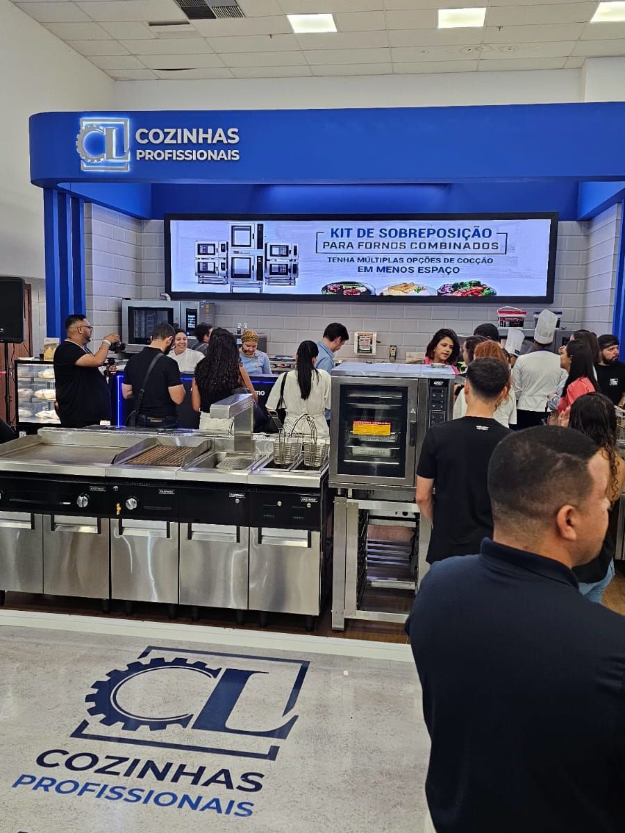 Um grupo de pessoas está em frente à cozinha de uma loja.