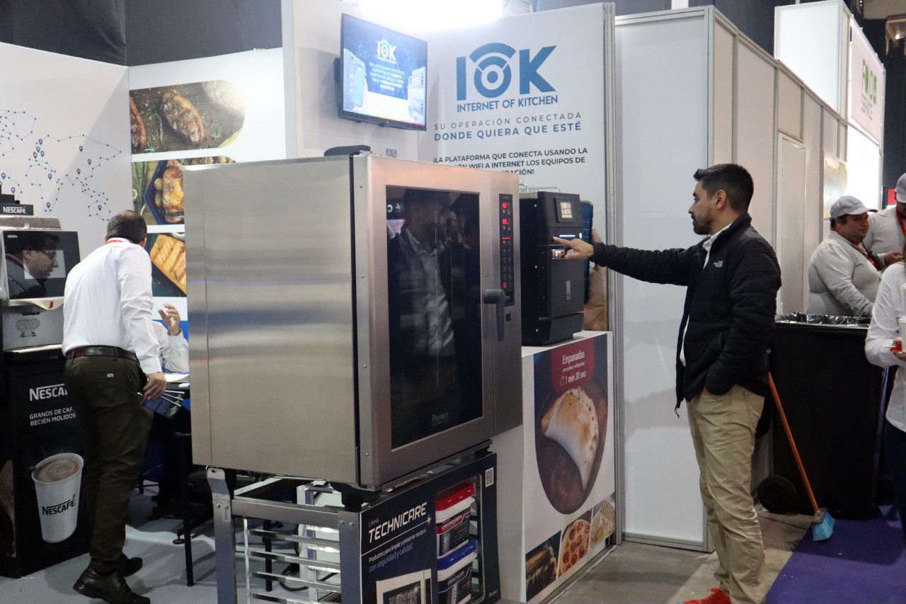 Um homem está em pé em frente a um grande forno de aço inoxidável.