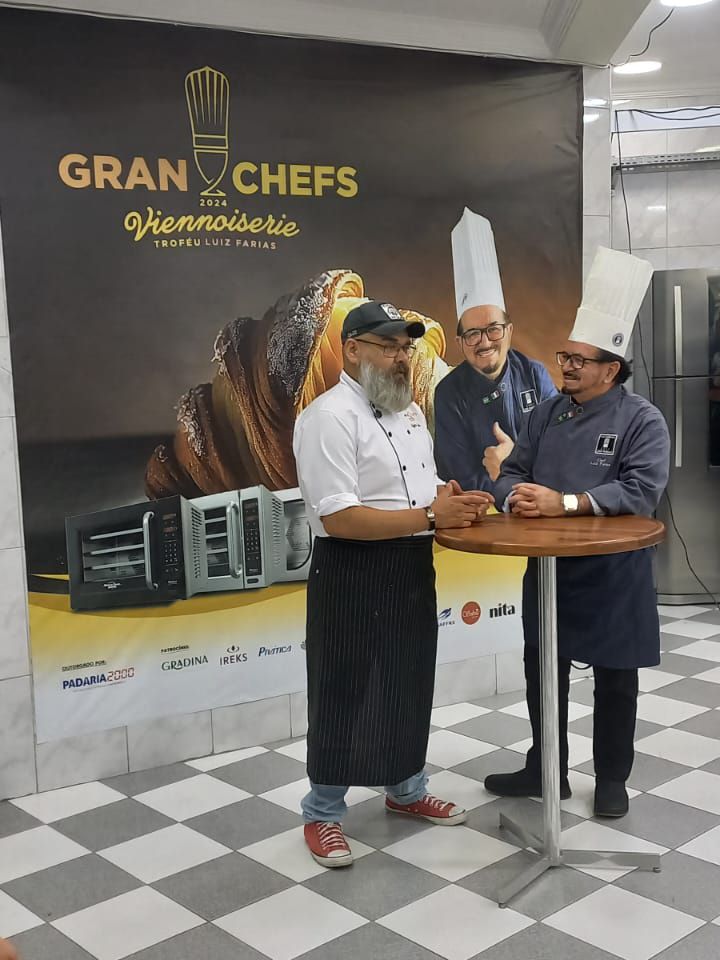 Três homens estão parados em frente a uma placa que diz gran chefs viennoiserie