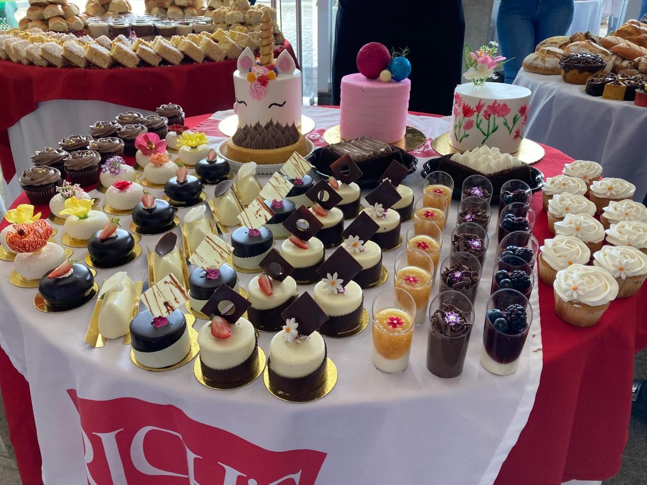 Uma mesa cheia de cupcakes e bolos com uma bandeira vermelha que diz 'gelo'