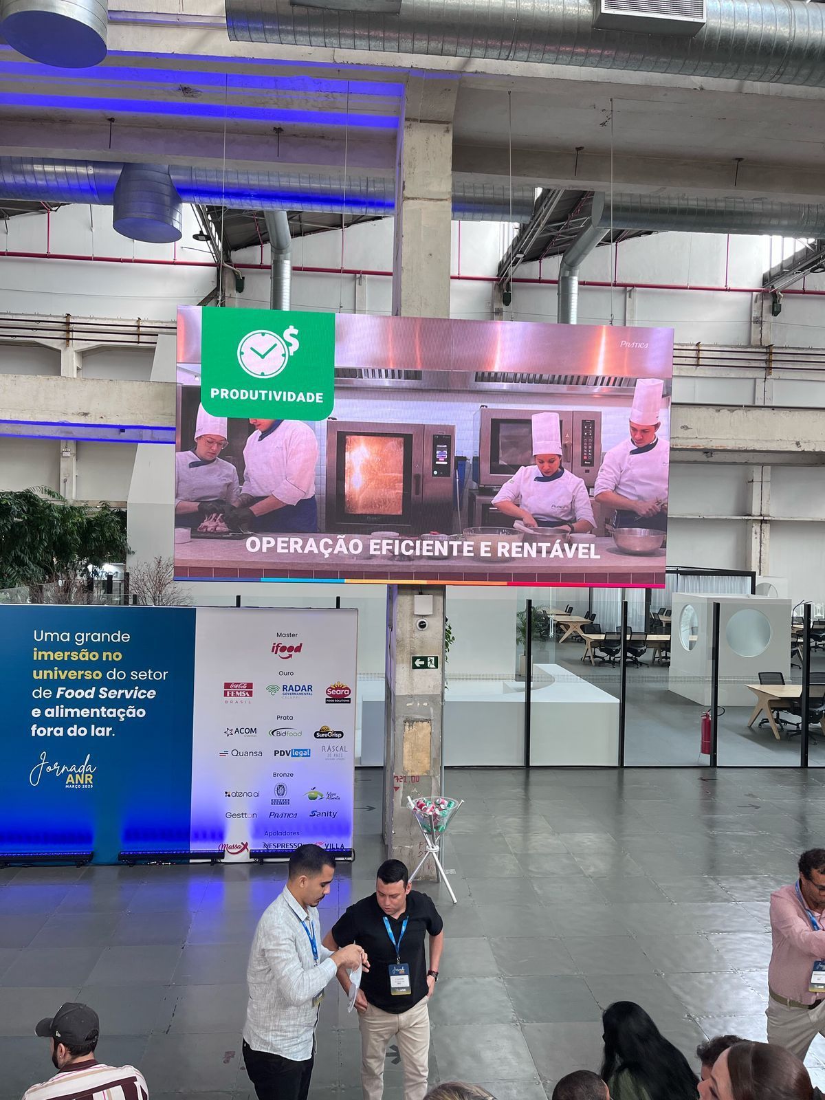 Um grupo de pessoas está em pé em frente a uma tela grande.