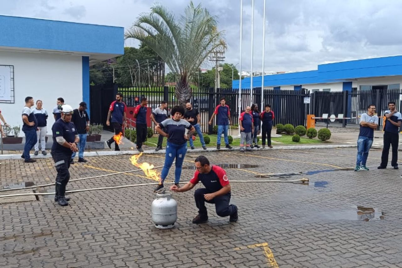 Um homem demonstra como extinguir um incêndio em um tanque de propano durante um exercício de treinamento de segurança ao ar livre.