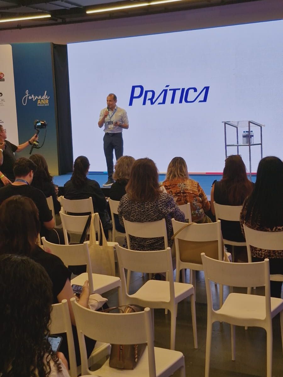 Um grupo de pessoas está sentado em frente a uma tela que diz prática