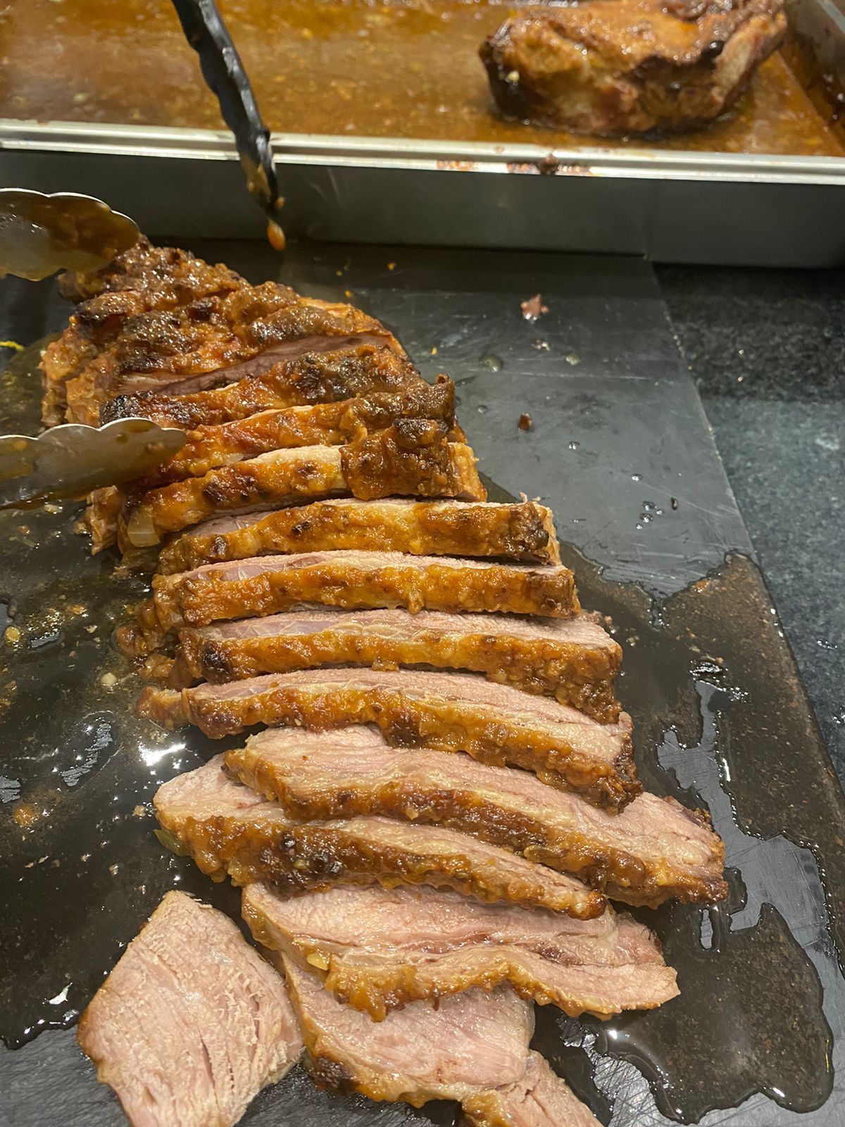 Um grande pedaço de carne está sendo fatiado em uma tábua de corte.