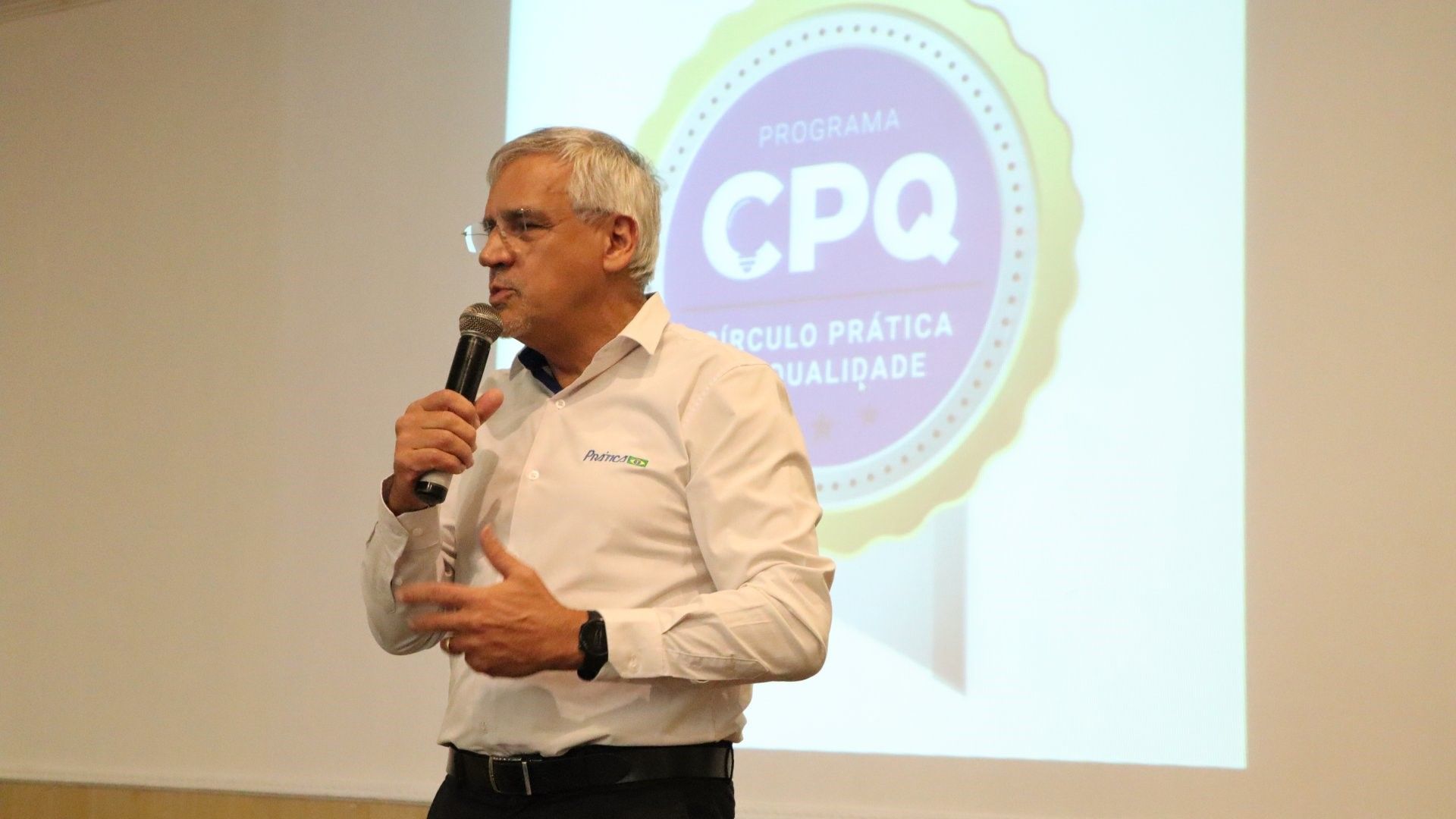 Um homem está em pé na frente de uma tela de projetor segurando um microfone.