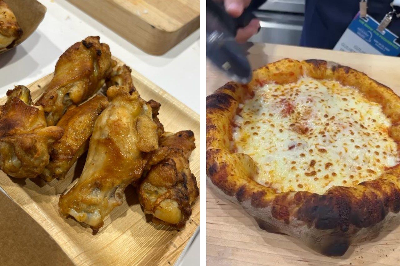 Um prato de asas de frango ao lado de uma pizza em uma mesa de madeira.