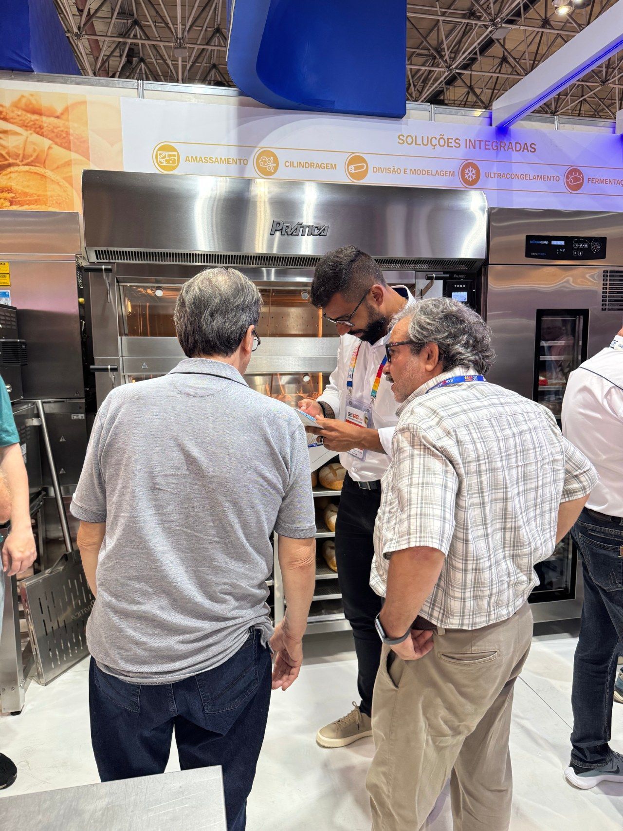 Um grupo de homens está em frente a um forno de aço inoxidável.