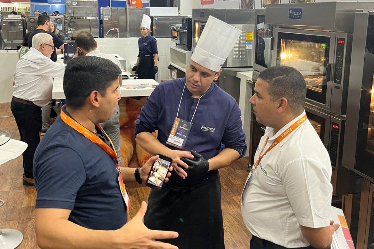 Um grupo de homens está em uma cozinha conversando entre si.