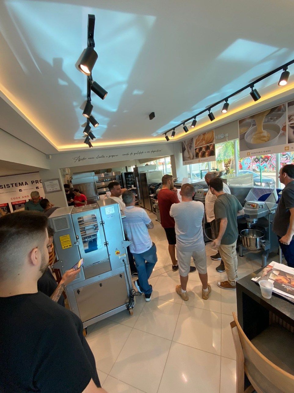 Um grupo de pessoas está em volta de uma máquina em um restaurante.