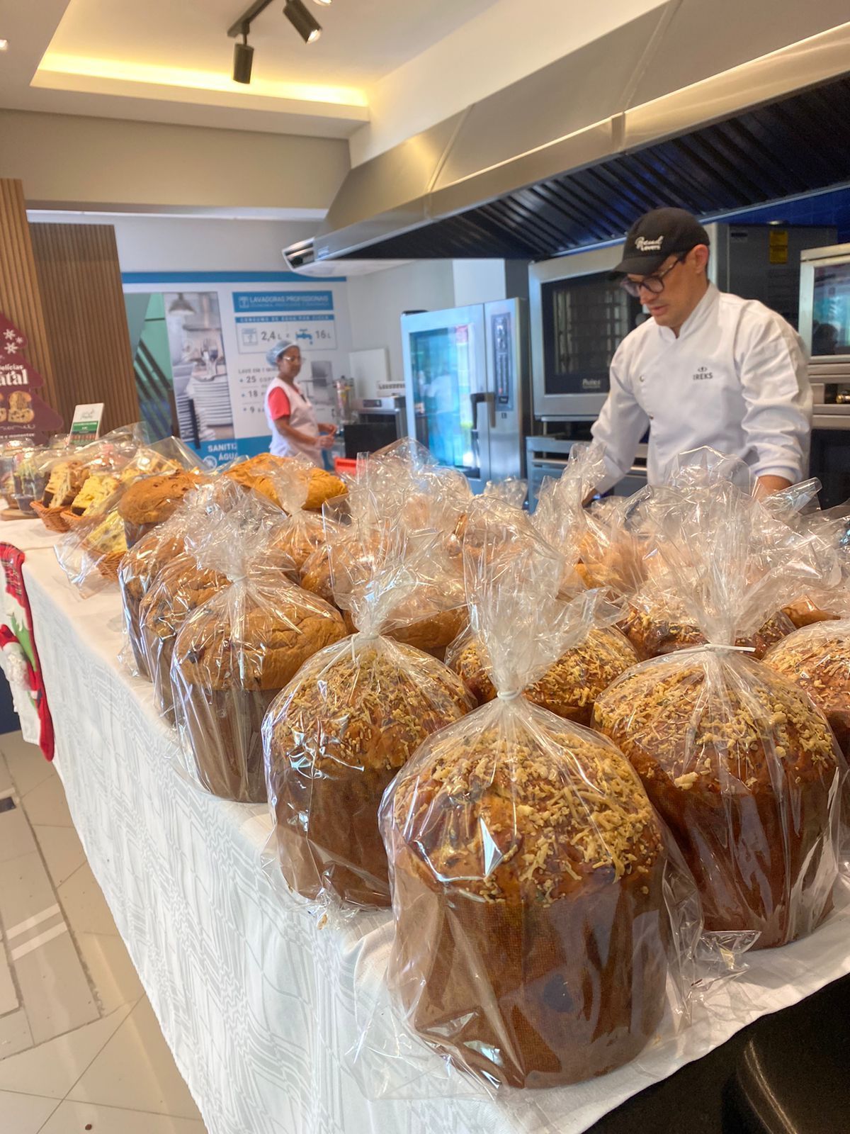 Um homem está de pé atrás de uma mesa cheia de sacos de pão.