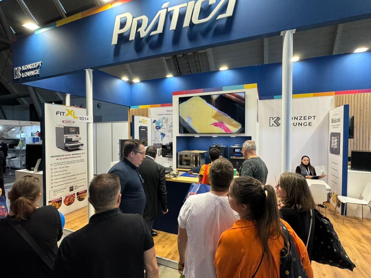 Um grupo de pessoas está em frente a um estande em uma convenção.