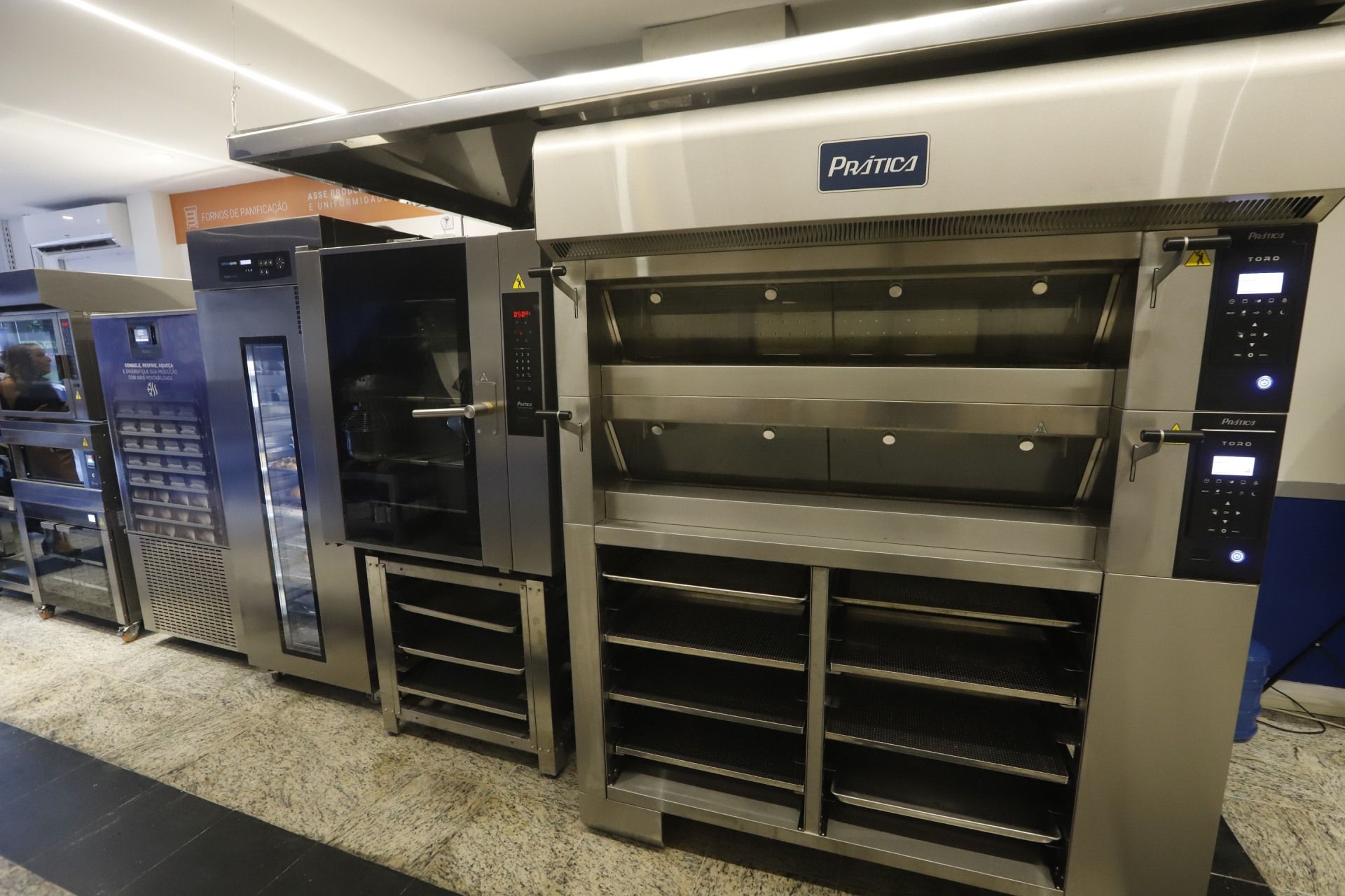 Vários fornos comerciais alinhados em uma loja, feitos de aço inoxidável.