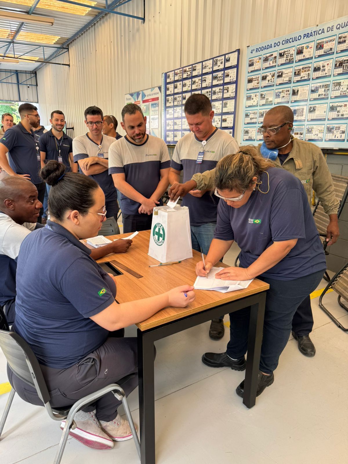 Um grupo de pessoas está sentado ao redor de uma mesa em uma sala.