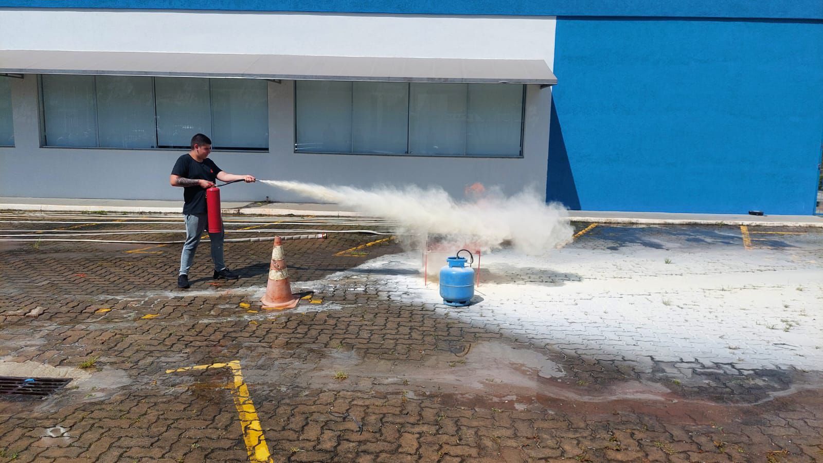 Um homem está usando um extintor de incêndio para apagar um incêndio em um estacionamento.