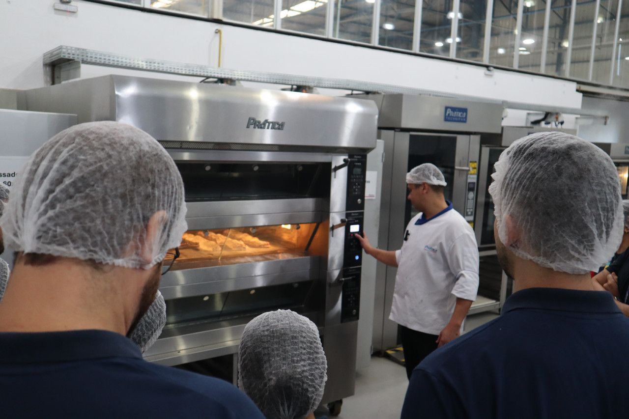 Um grupo de pessoas está em pé em frente a um forno.