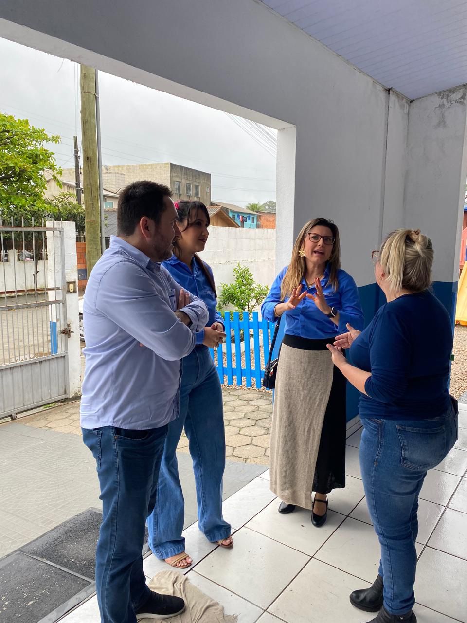 Um grupo de pessoas está de pé no chão de ladrilhos conversando entre si.