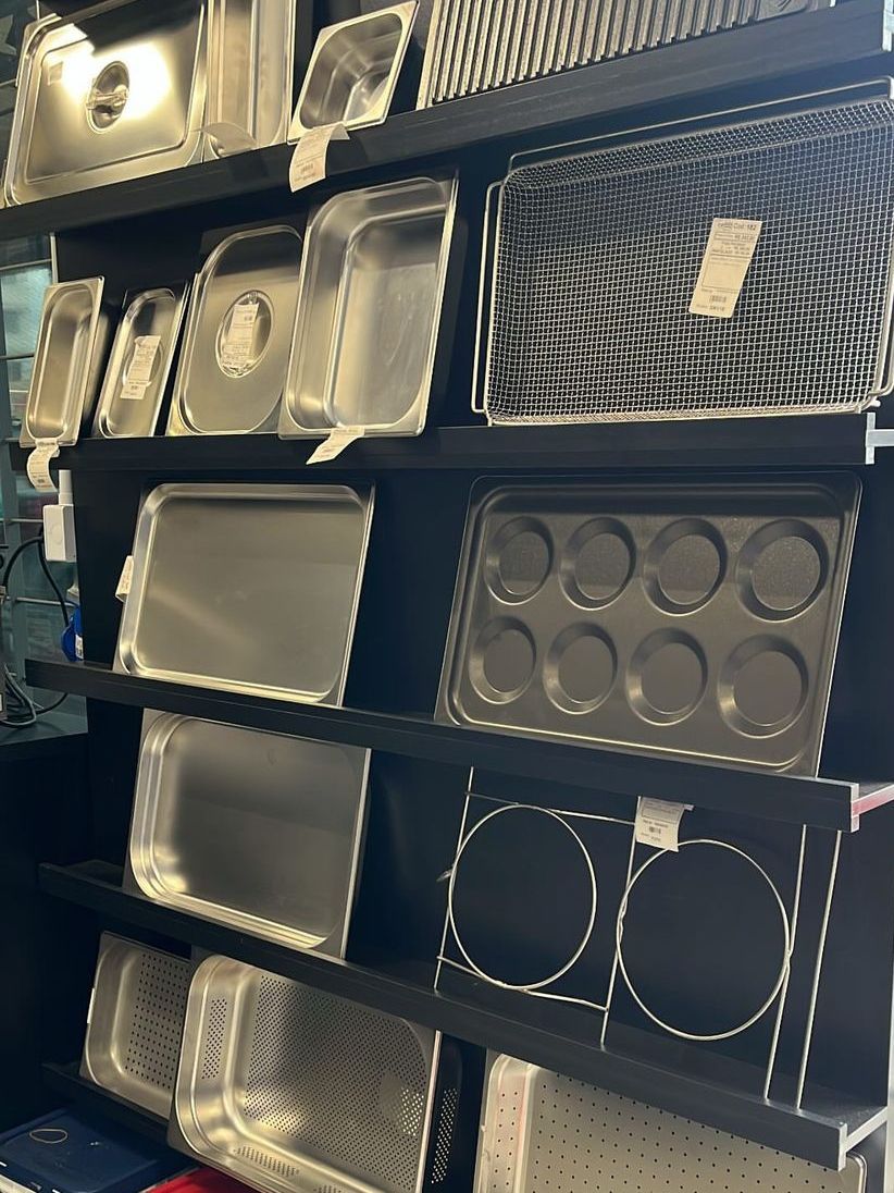 Uma prateleira cheia de uma variedade de panelas de aço inoxidável.