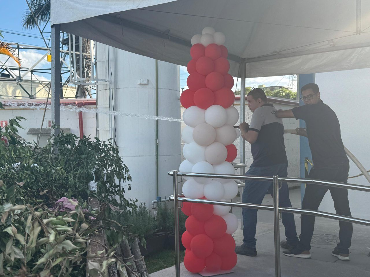 Dois homens estão trabalhando em uma torre de balões vermelha e branca