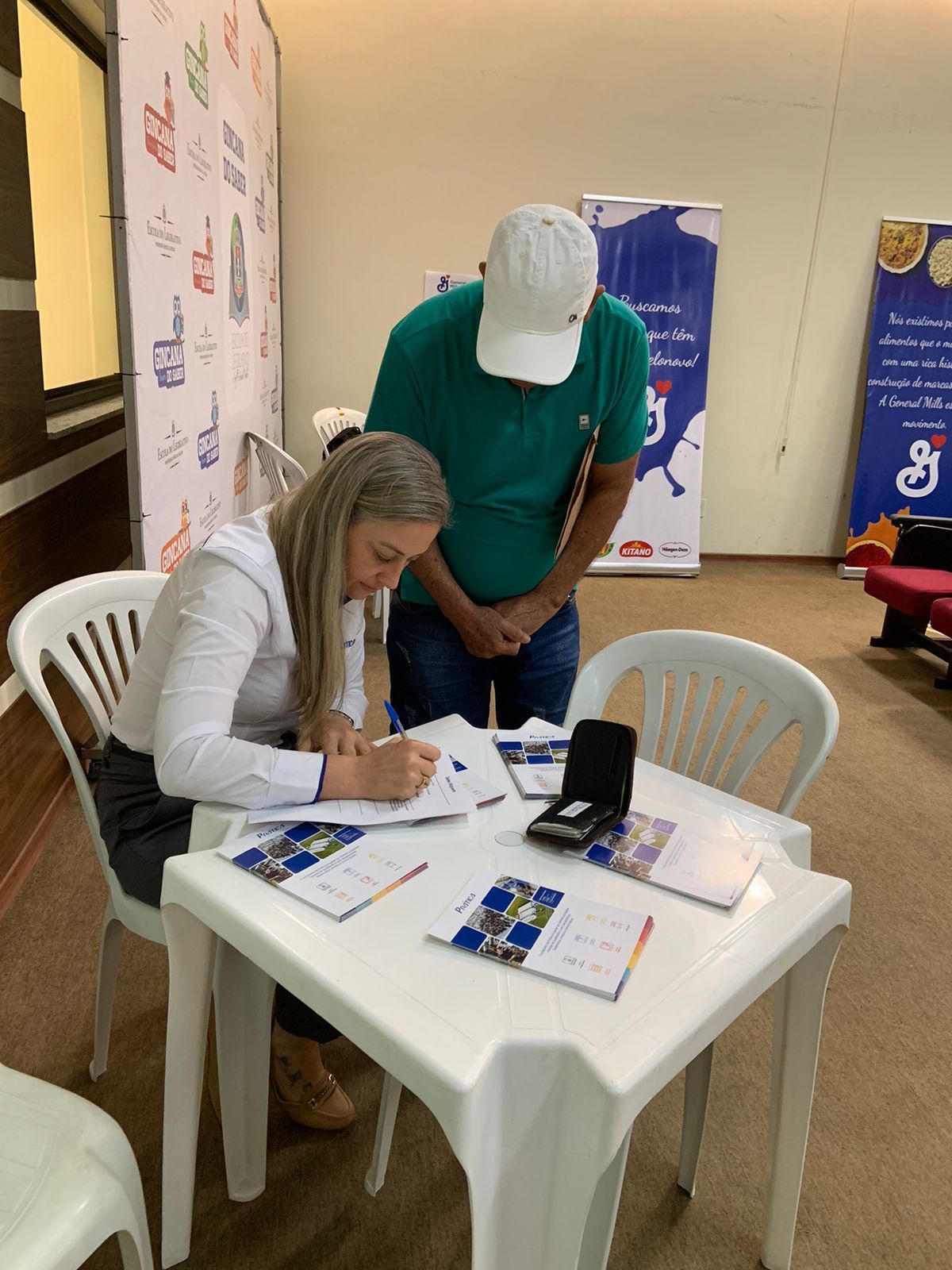 Um homem e uma mulher estão sentados à mesa assinando papéis.