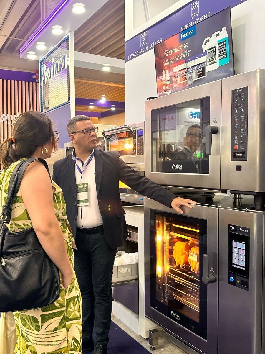 Um homem e uma mulher estão de pé ao lado de um grande forno.