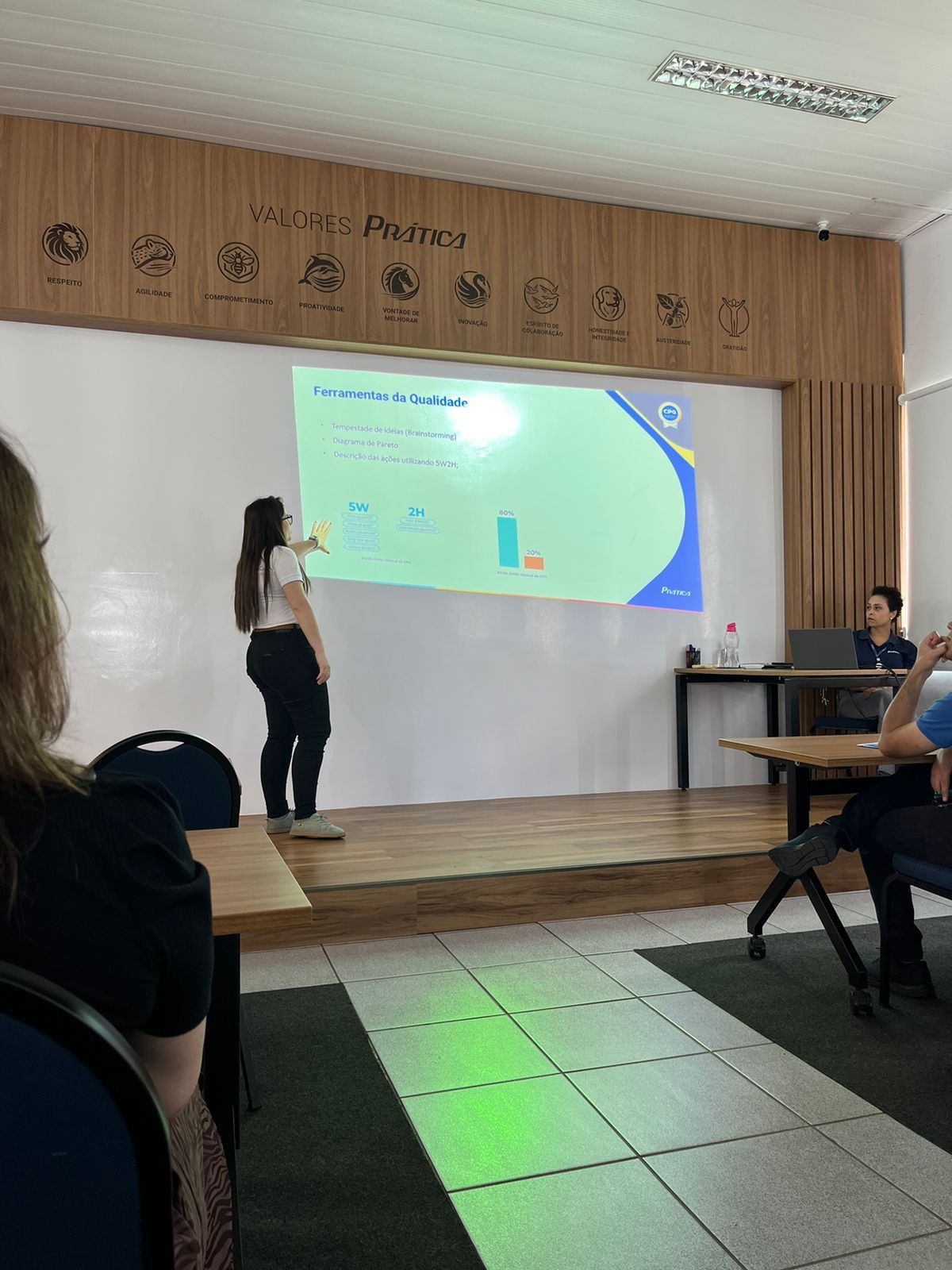 Uma mulher está fazendo uma apresentação em frente a uma tela de projetor.