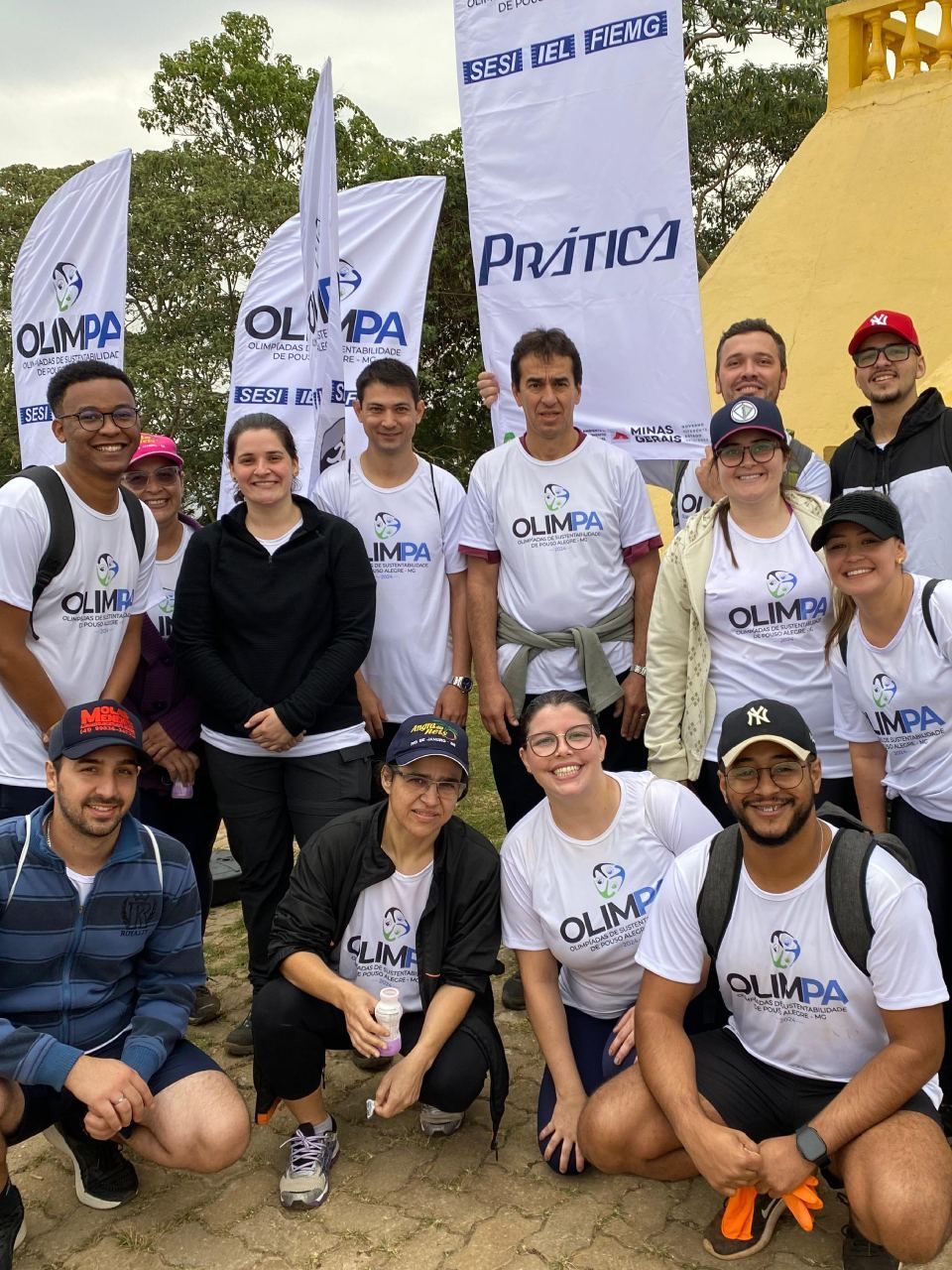 Um grupo de pessoas posando para uma foto com bandeiras ao fundo.