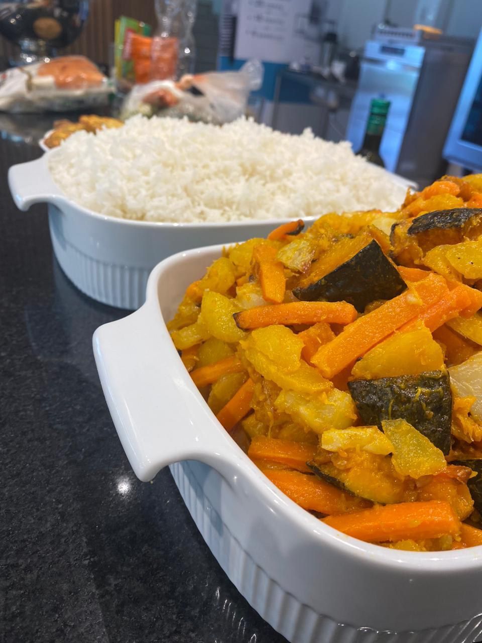 Uma tigela de cenouras e batatas ao lado de uma tigela de arroz