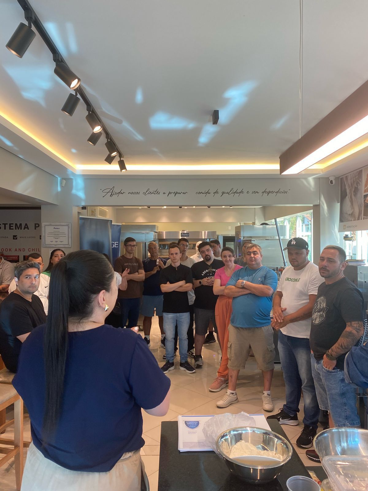 Um grupo de pessoas está em pé ao redor de uma mesa em uma sala.