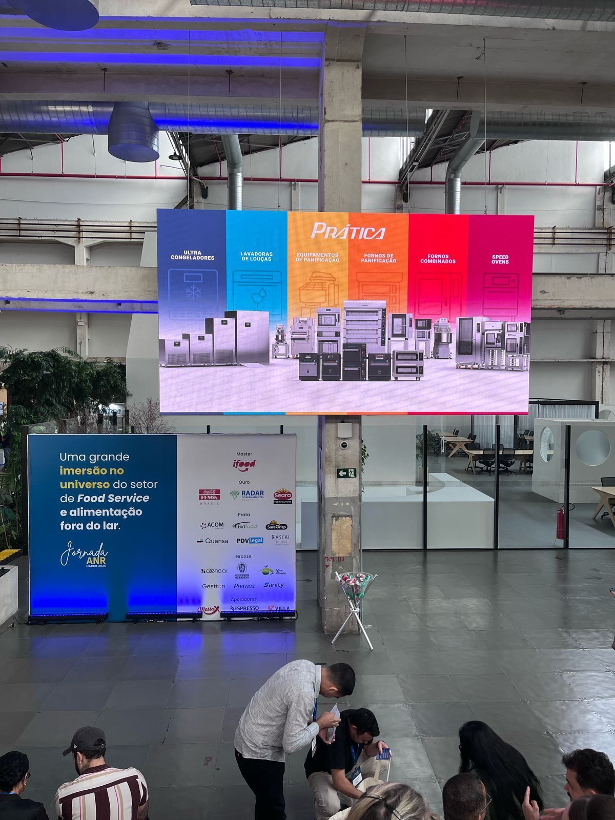 Um grupo de pessoas está sentado em frente a uma tela grande.