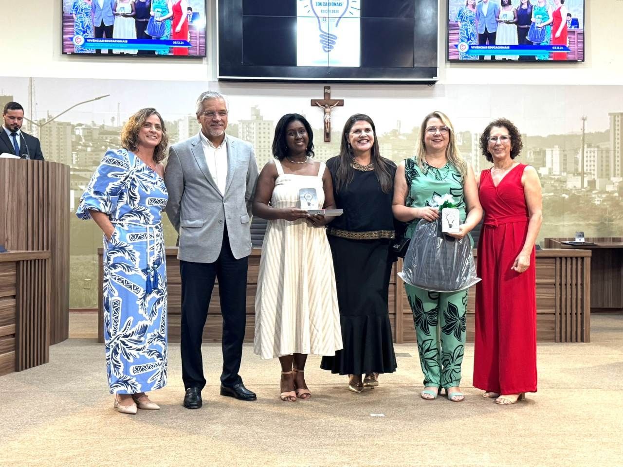 Um grupo de mulheres estão de pé, uma ao lado da outra, em uma sala.