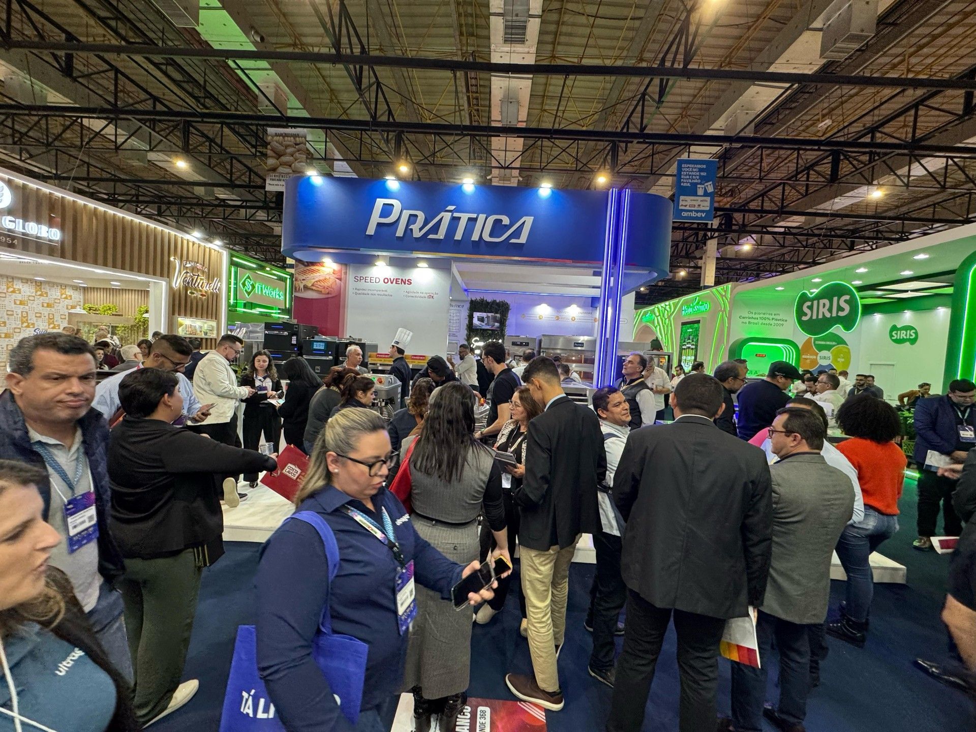 Um grande grupo de pessoas está em volta de um estande em uma convenção.