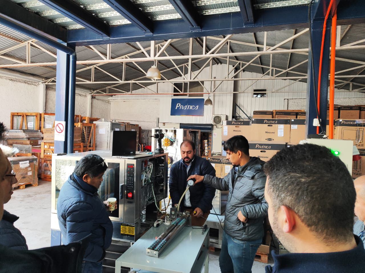 Um grupo de homens está em volta de uma máquina em um armazém.