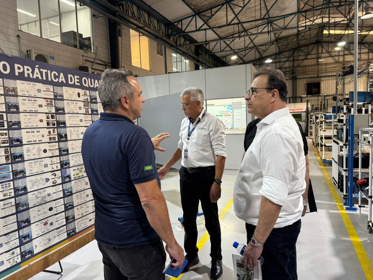 Um grupo de homens está em uma fábrica conversando entre si.