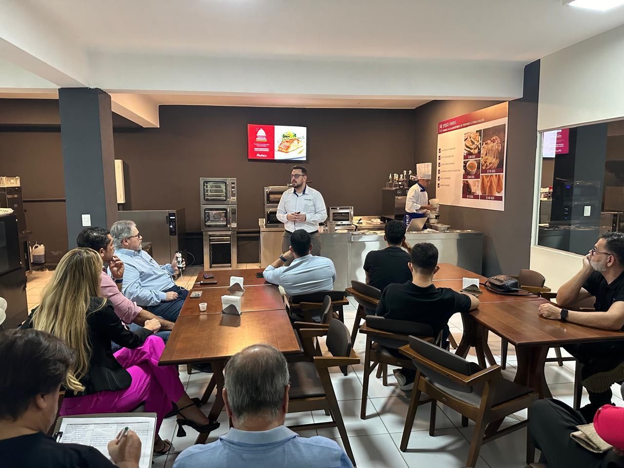 Um grupo de pessoas está sentado em mesas em uma sala.