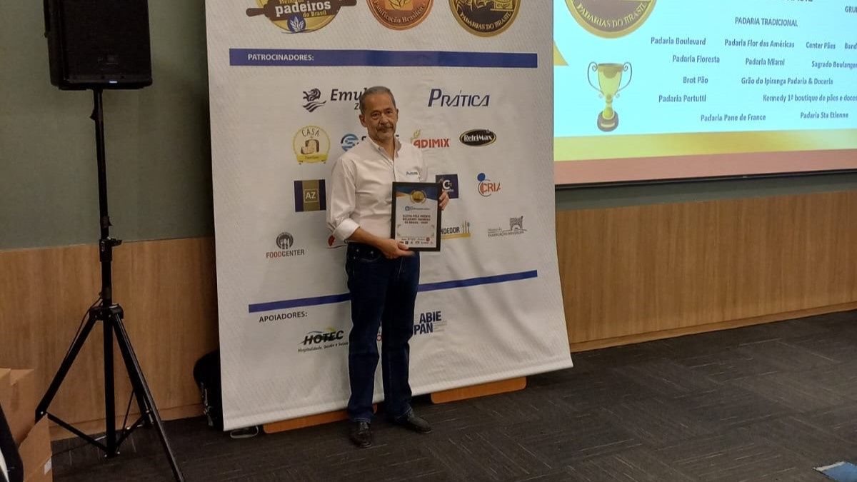 Um homem está de pé em frente a uma tela grande segurando um certificado.