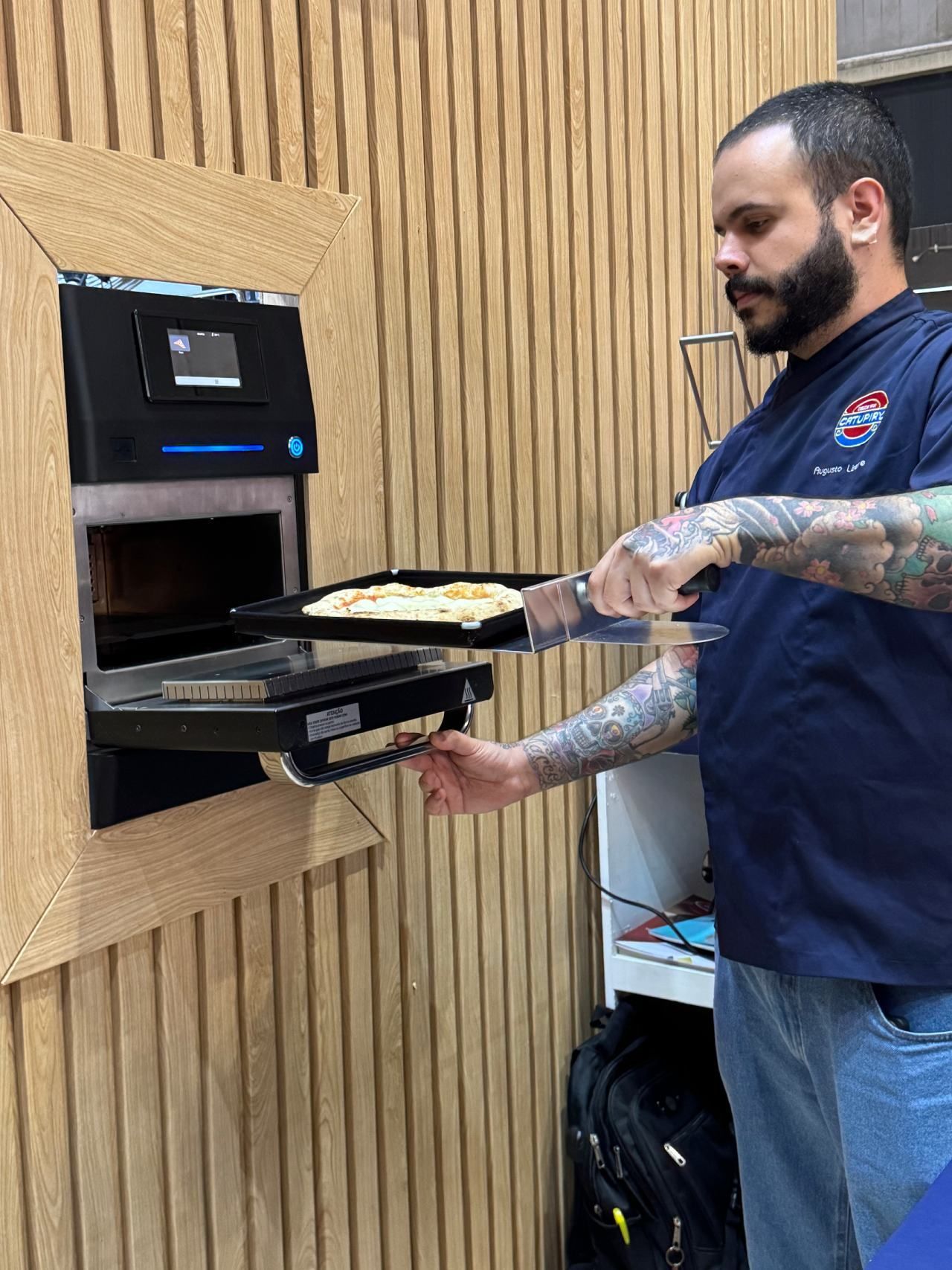 Um homem está tirando uma bandeja de pizza do forno.